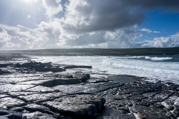 Doolin Pier in Ireland. A rocky landscape under a blue sky with clouds. In the background the Atlantic ocean. © Rob