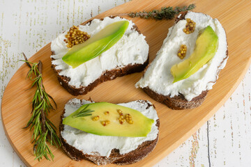 Vegetarian ricotta and avocado sandwiches with grainy mustard on a cutting board. Healthy snack