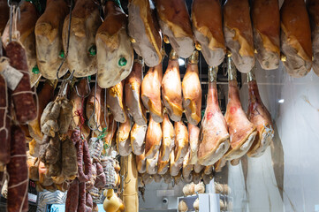 Traditional Italian dry-cured ham and sausages hanging from the ceiling of a local Neapolitan deli, showcasing authentic Mediterranean gourmet food culture.