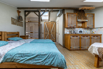 Rustic attic studio interior with twin beds and wooden kitchen