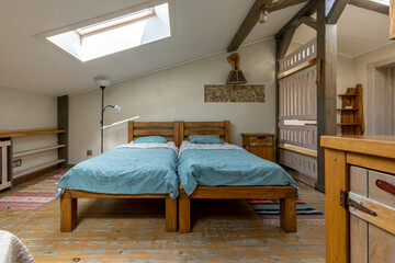 Rustic attic bedroom with twin beds and skylight window