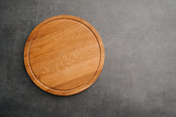 Round wooden chopping board with visible grain and rustic appearance, Circular wooden cutting platform with natural grain and warm tones for culinary presentation