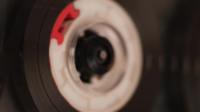 Macro close-up spinning audio cassette in vintage home stereo player retro 80s audio equipmen