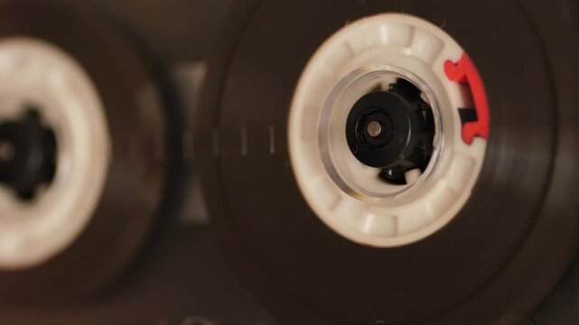 Macro close-up of vintage audio cassette spinning inside cassette player