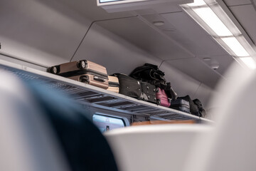 Various pieces of travel luggage are stored securely on the overhead rack inside a modern train cabin, symbolizing efficient public transport and passenger storage solutions