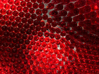 Vibrant red glass bottles artfully arranged and illuminated from behind, forming a captivating abstract pattern and modern design installation, evoking luxury and celebration