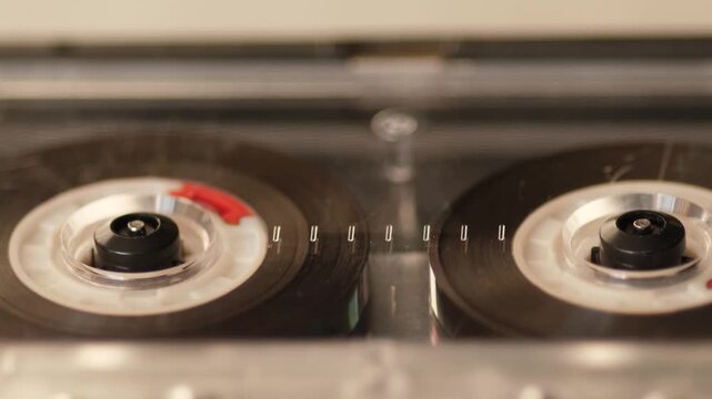 Macro close-up of retro audio cassette playing music in analog tape deck, shallow depth of field