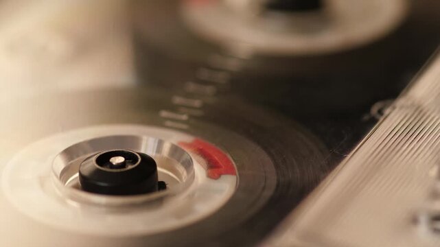Macro close-up of vintage audio cassette tape spinning in audio player, shallow depth of field