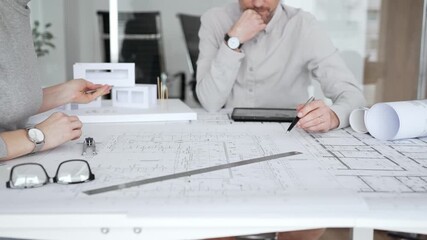 Architects are teamwork planning a building design project, reviewing detailed blueprints with a compass and a ruler, working on technical drawings and a digital tablet at the office, close up - Powered by Adobe