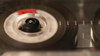 Macro close-up of vintage audio cassette playing in tape deck, magnetic tape moving on spools, retro music technology