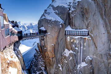 People on the bridge at the top of the Aiguille du Midi, snow-capped mountain peaks in the Alps, Chamonix-Mont-Blanc.