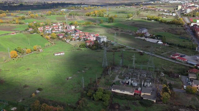 Autumn aerial video of Kor&ccedil;&euml;&rsquo;s rural edge showing open fields, a village and an electrical substation beneath bright seasonal light.