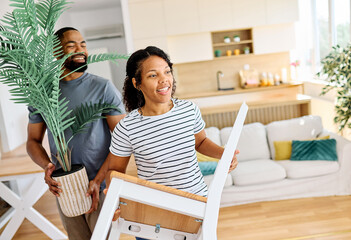Young black couple moving into a new modern house, carrying boxes and arriving home together. Happy, excited and smiling husband and wife walking, entering and relocating after buying an apartment