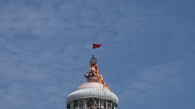 Sacred flag flying atop Jagannath Temple against blue sky, Puri, India