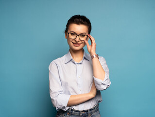 Middle aged smiling happy successful employee business woman wear shirt glasses, isolated on light blue background