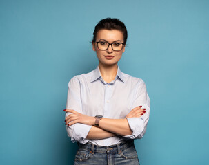 Middle aged smiling happy successful employee business woman wear shirt glasses, isolated on light blue background