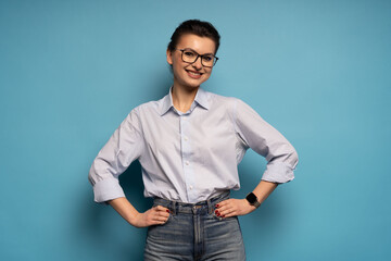 Middle aged smiling happy successful employee business woman wear shirt glasses, isolated on light blue background