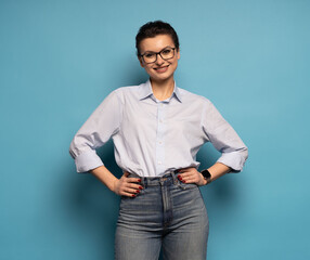 Middle aged smiling happy successful employee business woman wear shirt glasses, isolated on light blue background