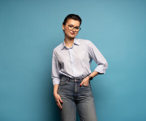 Middle aged smiling happy successful employee business woman wear shirt glasses, isolated on light blue background