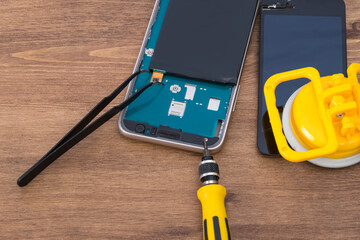 gadget repair tools and a disassembled phone display with a battery