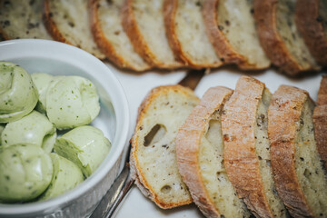 Freshly sliced artisan bread arranged neatly beside a bowl of herb-infused butter balls, creating a delightful culinary presentation for gourmet dining experiences