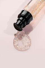 Fluid cosmetic product 24k gold gel in a glass bottle on beige background. Beauty serum, peptides, essence, wellness ads, cosmetic presentations. Skin care, face cream, mask, body lotion, moisturizer