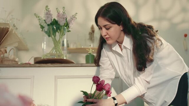 Young female florist arranging fresh flower bouquets in a flower shop. Captures hands-on work, selecting flowers, arranging colors, Perfect for lifestyle, small business, floral design, retail . 