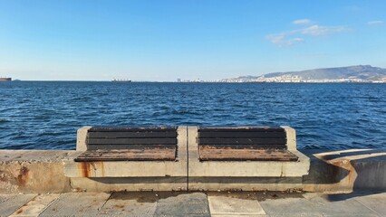 Fototapeta premium Empty concrete bench by the sea on a clear day