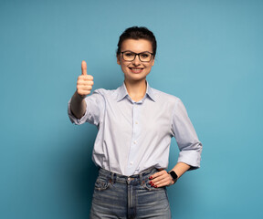 Portrait of positive woman with thumb up sign gesture isolated on blue background.