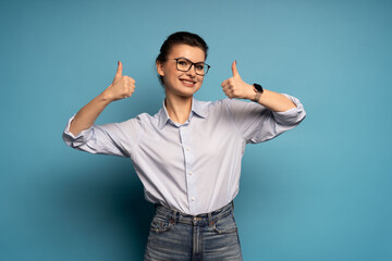 Portrait of positive woman with thumb up sign gesture isolated on blue background.