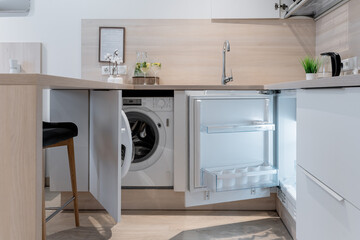 the area of the built-in small kitchen. There is a washing machine and a small fridge in the kitchen. refrigerator with an open door