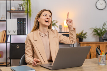 Middle-aged businesswoman at home office preps presentation on laptop finds idea says eureka smiles with new drive. Freelancer girl at table drafts outline builds slides sets plan for deck keeps focus