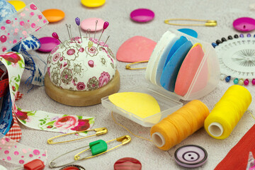Sewing accessories. Pincushion, fabric chalk, buttons, and pins on a table. Craft supplies.