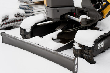 Industrial construction machinery close up showing excavator tracks hydraulic components and dozer blade covered with snow on winter worksite ground © K