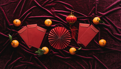 Celebrating the Lunar New Year with red envelopes, oranges, and a traditional fan on a textured red background