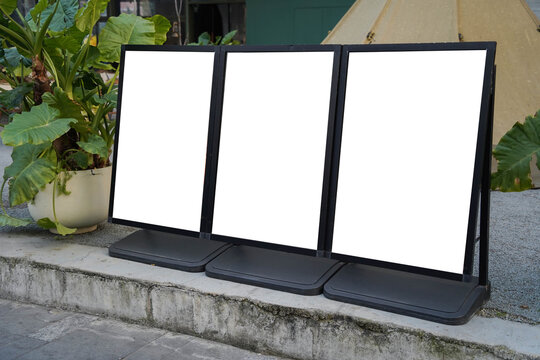 Three blank white outdoor advertising stand or sandwich boards mock up template placed by an indoor building