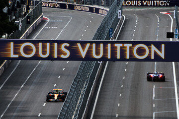 Naklejka premium BAKU, AZERBAIJAN - SEPTEMBER 19, 2025: A McLaren F1 car and a Williams Racing car on the track under a prominent Louis Vuitton sponsorship banner during the Formula 1