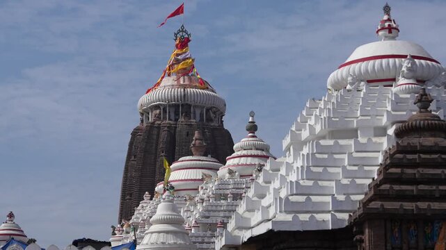 Jagannath Temple complex with multiple shrines and main tower under blue sky in Puri, India
