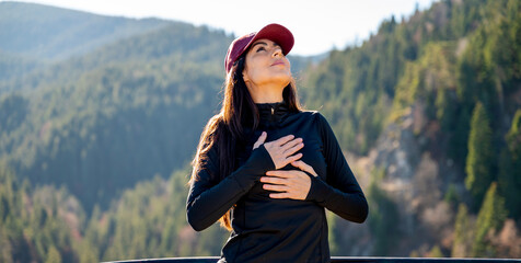 Relaxed woman breathing fresh air in a green pine forest and making breathing exercises 