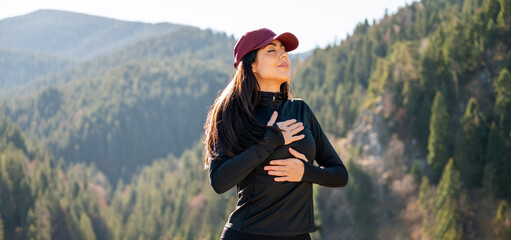 Relaxed woman breathing fresh air in a green pine forest and making breathing exercises 