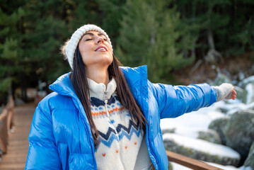Beautiful woman breathing fresh air in a snowy winter mountain