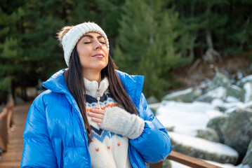 Beautiful woman breathing fresh air in a snowy winter mountain
