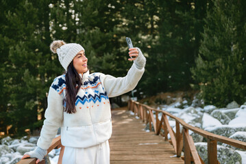 Beautiful Woman taking selfie pictures with her  phone in the Winter Mountain 