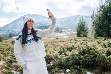 Beautiful Woman taking selfie pictures with her  phone in the Winter Mountain 