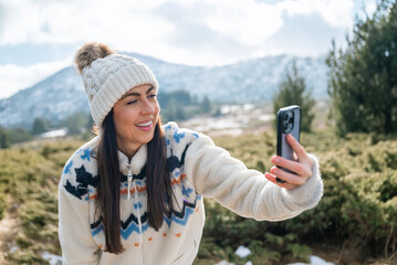 Beautiful Woman taking selfie pictures with her  phone in the Winter Mountain 