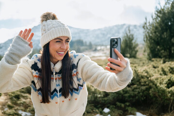 Beautiful Woman taking selfie pictures with her  phone in the Winter Mountain 