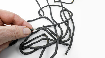 Worn out black shoe lace on a white