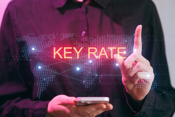 Person uses a smartphone to display key rate information against a digital world map at a workspace during the day