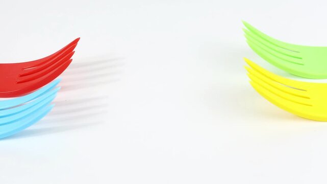 Colorful plastic forks with white background, copy space in the center.