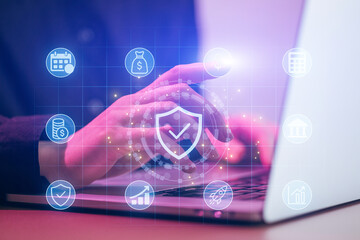 Professional working on laptop with digital financial icons and security symbols in office setting at daytime